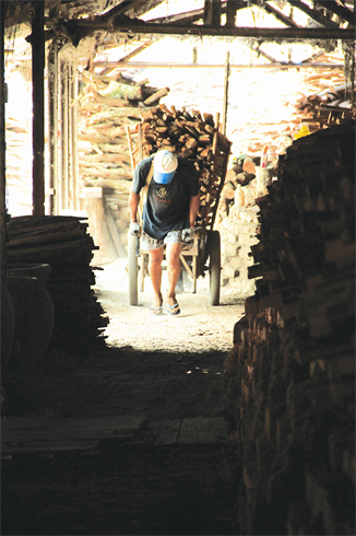 Un ouvrier achemine du bois pour alimenter le foyer du four.    