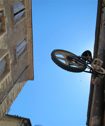 Un vieux BMX découpé et accroché à un mur dans une vieille rue. L’art de la rue apporte à la Comédie sa beauté insolite.  