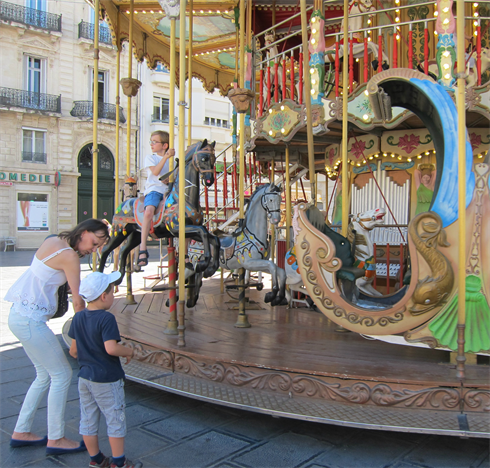 Les enfants jouent dans le manège installé sur la place de la Comédie vieux d’un quart de siècle. 