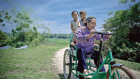 Une grand-mère se promène avec ses deux petits-enfants dans le village.    